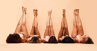 Buy stock photo Skincare, diversity and legs of women in studio for care, comparison and wellness on wall background. Difference, beauty and female friends relax in a line with feet up for glowing skin or treatment