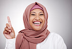 Pointing up, portrait and a Muslim woman on a studio background with a smile for a question. Happy, headshot and an Arab person or business employee with a finger for a vote isolated on a backdrop