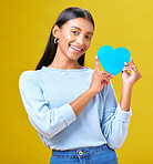 Portrait, donation and woman with blue heart in studio for help, hope or empathy on yellow background. Face, charity and social media, poster or thank you, support or autism or people with disability