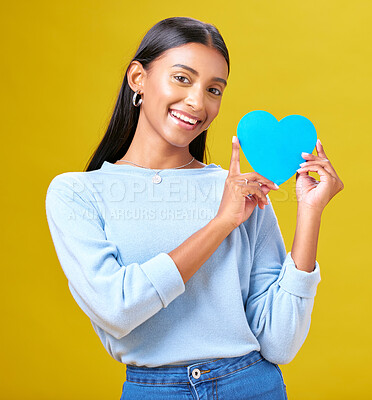 Buy stock photo Portrait, donation and woman with blue heart in studio for help, hope or empathy on yellow background. Face, charity and social media, poster or thank you, support or autism or people with disability