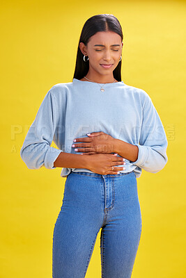 Buy stock photo Sick, stomach pain and woman with constipation, digestion problem or diarrhea in studio isolated on a yellow background. Abdomen gas, disease and person with menstrual cramps, endometriosis or hernia
