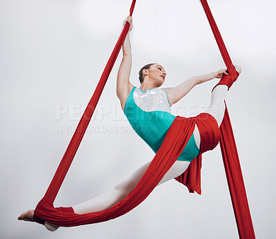 Flexibility, aerial silk and acrobat woman in air for performance, sports and balance. Gymnastics, athlete person or gymnast hanging on red fabric and white background with space, art and creativity