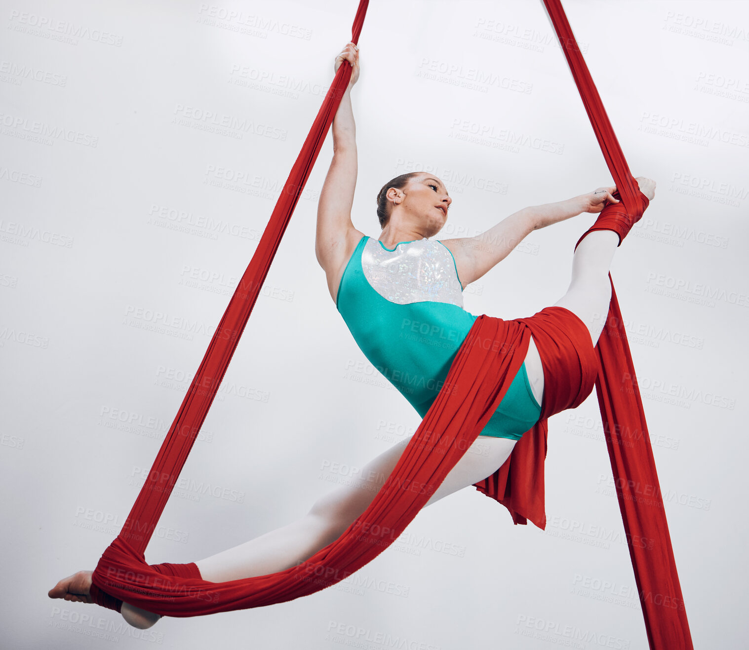 Buy stock photo Flexibility, aerial silk and acrobat woman in air for performance, sports and balance. Gymnastics, athlete person or gymnast hanging on red fabric and white background with space, art and creativity