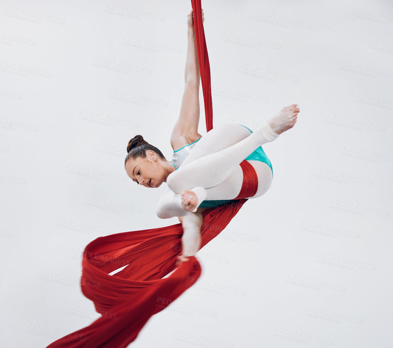 Buy stock photo Acrobat, gymnastic and aerial silk with a woman in air for performance, sports and balance. Young athlete person or gymnast hanging on red fabric and white background with space, art and creativity