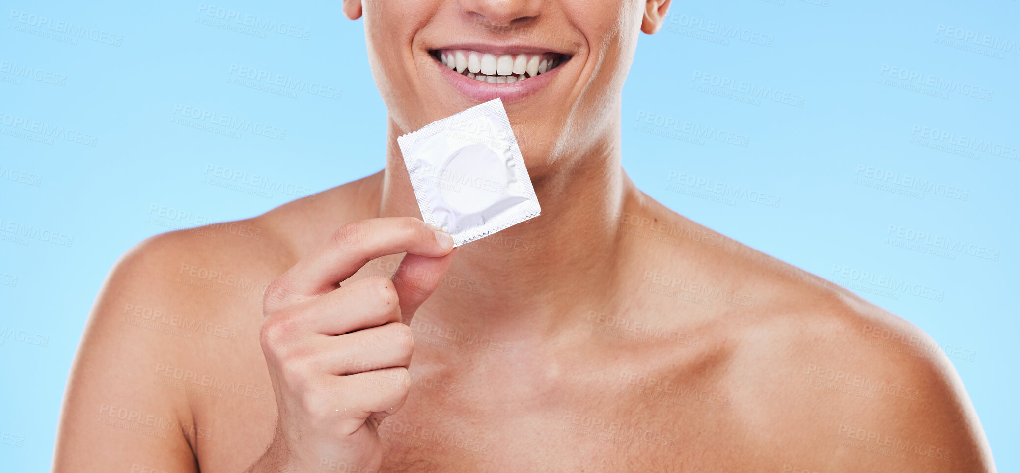 Buy stock photo Smile, hand and man with a condom on a blue background for security or birth control in sex. Happy, health and person or guy showing protection or a product for sexual safety choice or contraception