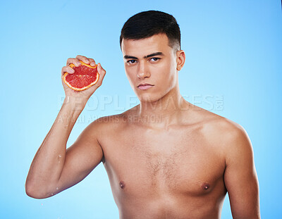 Buy stock photo Squeeze, grapefruit and skincare with portrait of man in studio for health, detox and natural cosmetics. Vitamin c, nutrition and spa with person and fruit on blue background for self care and glow 