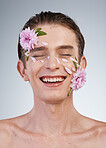 Happy, skincare and flowers on face of man in studio for spring, natural cosmetics and creative. Glow, self love and floral beauty with model on white background for makeup, spa treatment or wellness