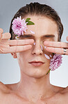 Beauty, cover and flowers on face of man in studio for spring, natural cosmetics and creative. Glow, self love and floral with model on white background for makeup, spa treatment and wellness