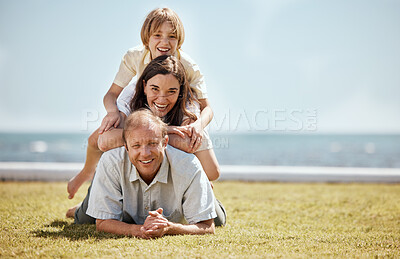 Buy stock photo Portrait, mockup and family in a pile on grass by the ocean together for travel, vacation or holiday in a summer. Love, smile or happy with a dad, mom and son on the ground in a stack at the sea