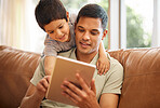 Father, boy and child with tablet on sofa for online games, reading ebook story and elearning multimedia. Man, dad and happy kid streaming cartoon, movies or digital technology in living room at home