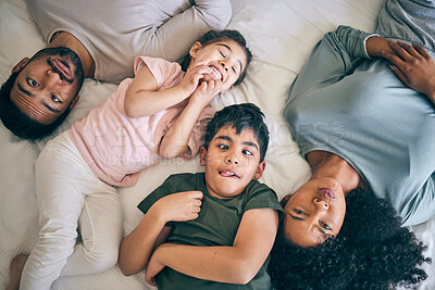 Buy stock photo Top view, face and funny family in bed at home together, bonding to relax or having fun. Portrait, laughing and mother, father and children in bedroom, smile and happy for comedy in interracial house