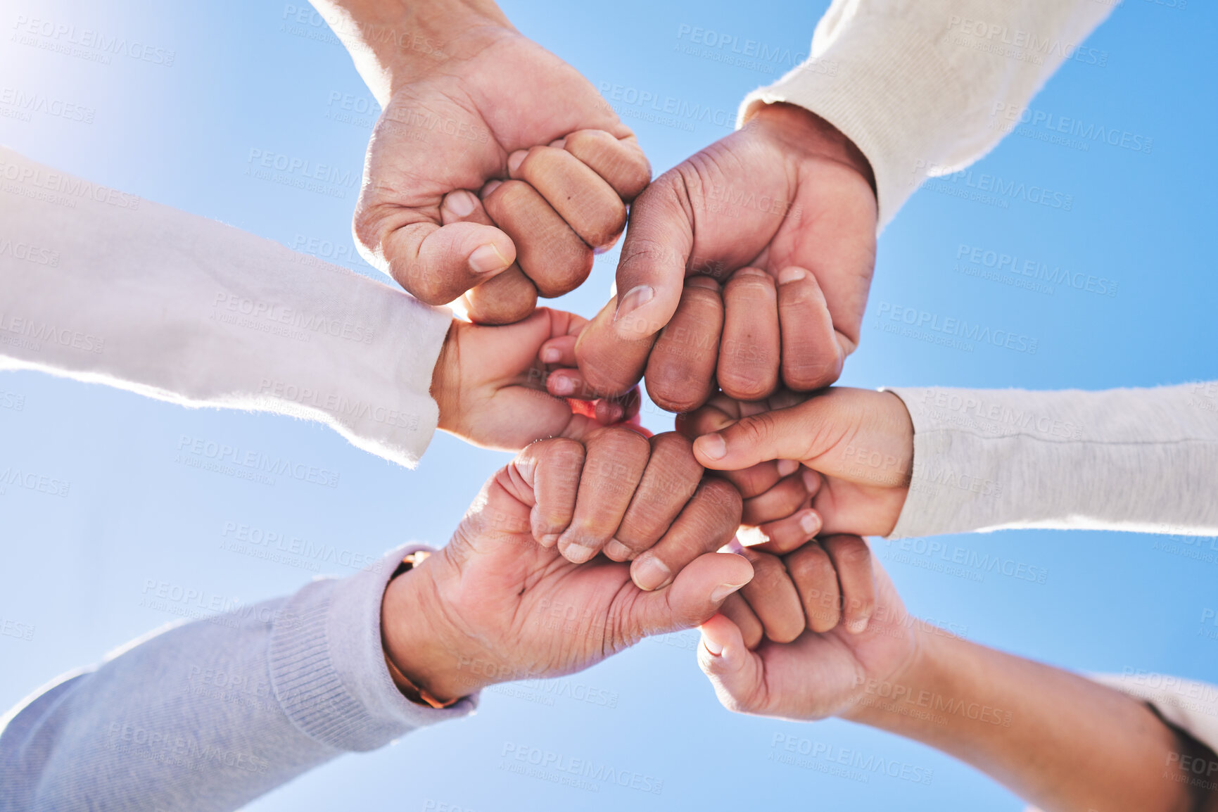 Buy stock photo Hands in circle, blue sky and diversity for community in collaboration for global support and success. Teamwork, fist and bottom view of group of friends with positive vision, trust and love outdoors