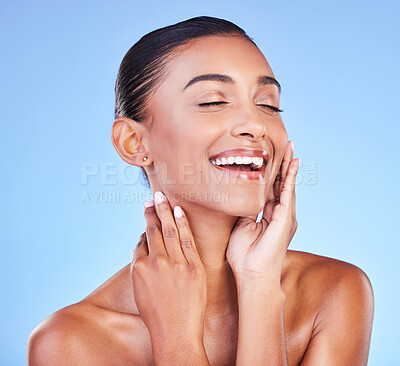 Buy stock photo Skincare, beauty and face of happy woman in studio with blue background and dermatology or cosmetics for healthy glow. Indian, model and happiness with hands on natural skin, facial or self care