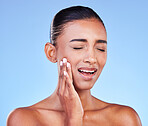 Dental hygiene, pain and woman with toothache, cavity and plaque on a blue studio background. Person, girl and model with oral care, touching her sore cheek and medical issue with emergency or crisis