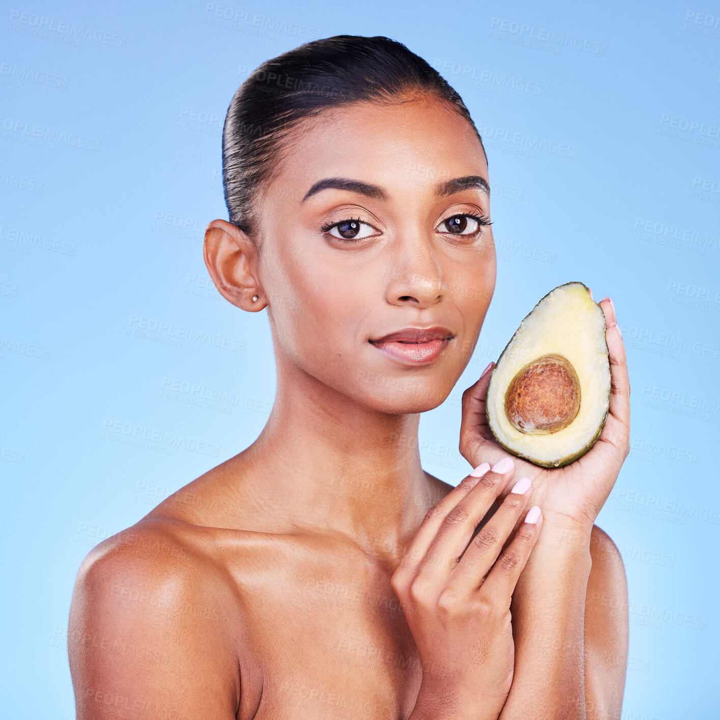 Buy stock photo Avocado, beauty and portrait of woman in studio for cosmetics, nutrition and diet on blue background. Indian model, skincare and fruit for sustainable dermatology, vegan wellness and facial benefits 