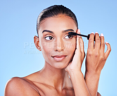 Buy stock photo Woman, mascara and makeup, beauty and brush with transformation and cosmetic product on blue background. Eyelash extension, cosmetology and volume with Indian model, wellness and change in a studio