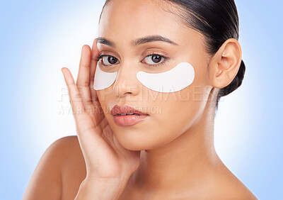 Buy stock photo Portrait, skincare and eye mask with a natural woman in studio on a blue background for antiaging treatment. Face, beauty and wellness product with a young model at the salon for a facial application