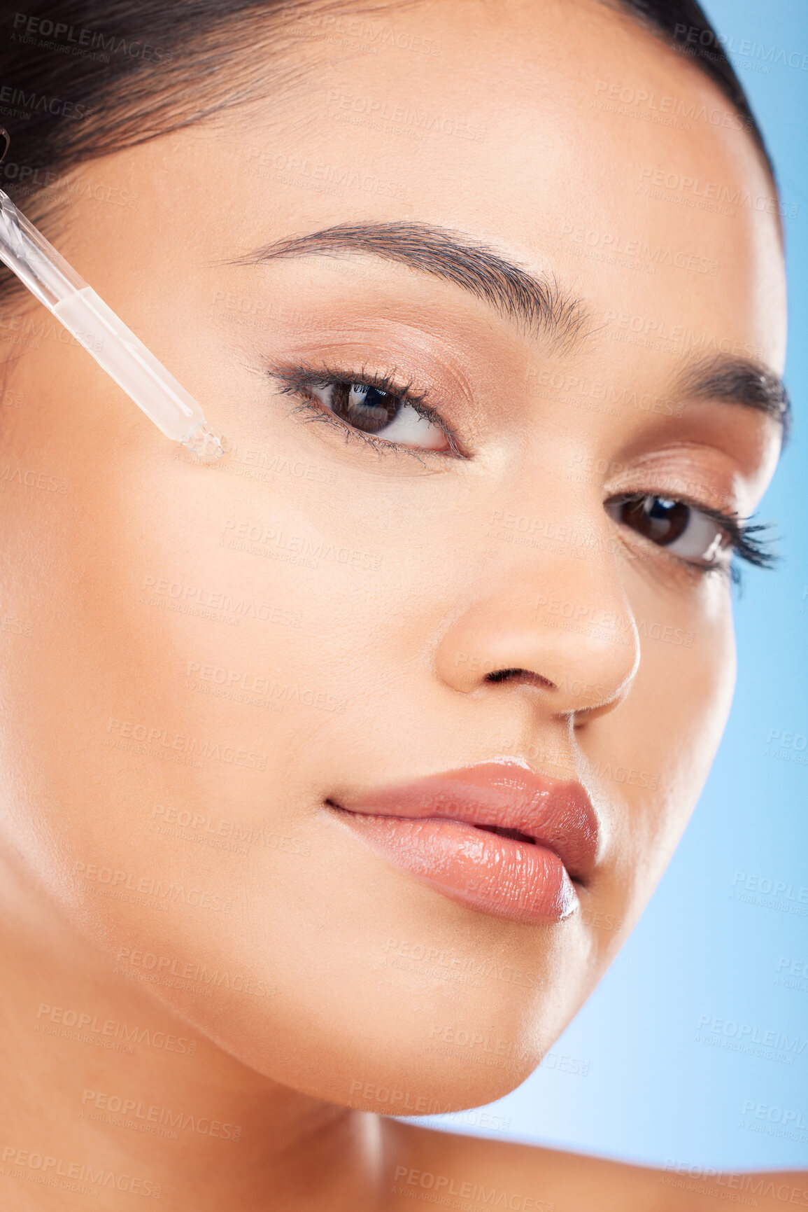 Buy stock photo Woman, portrait and essential oil for beauty, skincare and cosmetics product on a blue background. Young person with facial serum, dermatology dropper or collagen for skin care on face in studio