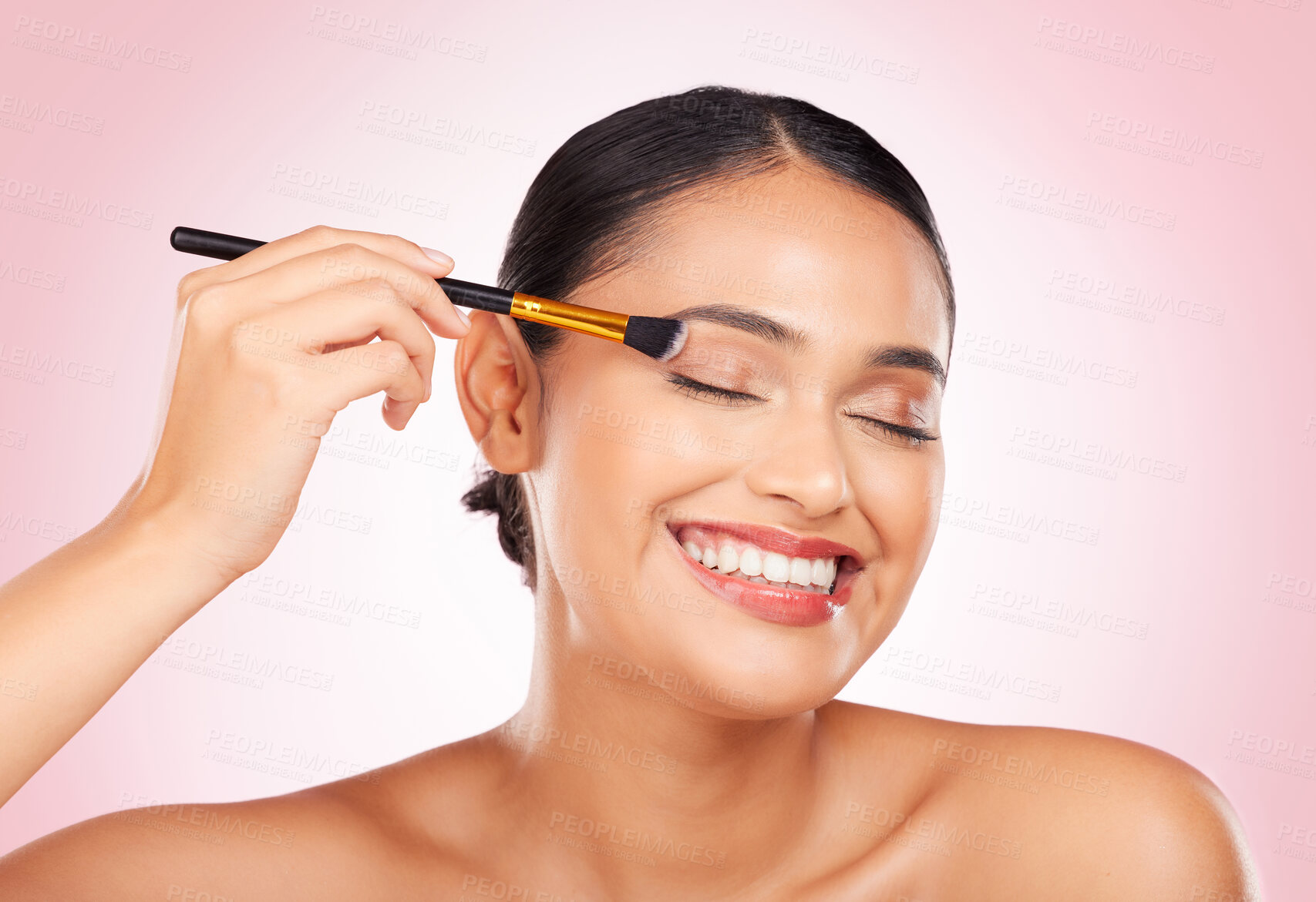 Buy stock photo Happy, beauty and a woman with a brush on a pink background for skincare, wellness and health. Smile, young and a female model with makeup, eyeshadow or foundation on face for cosmetics on a backdrop