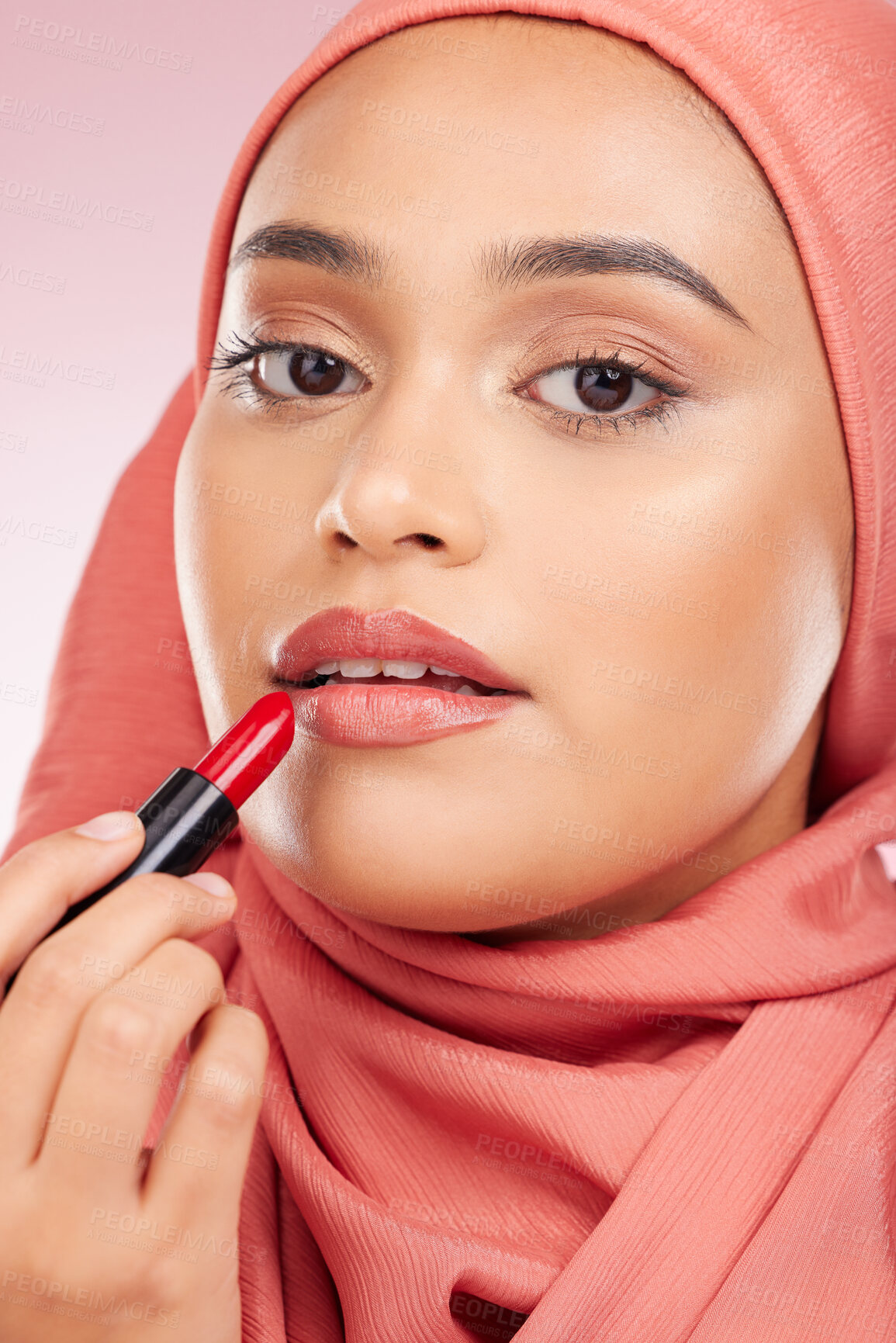 Buy stock photo Portrait, beauty and lipstick with a muslim woman closeup in studio on a pink background for cosmetics. Face, makeup and islamic with a young model in an hijab to apply a product for red color