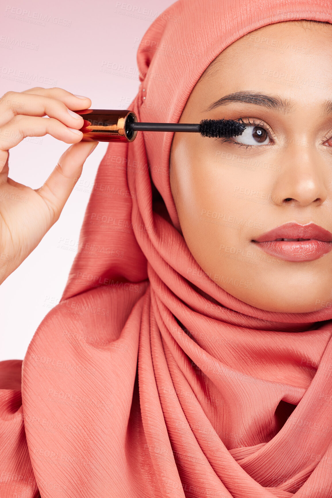 Buy stock photo Beauty, luxury and mascara with a muslim woman closeup in studio on a pink background for cosmetics. Makeup, eyelash and brush with a young islamic model getting ready to apply cosmetics to her face