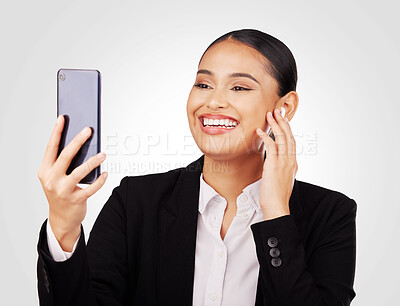 Buy stock photo Video call, phone and earphones with a business woman in studio on a white background for communication. Smile, networking and music with a happy young employee reading a text message on her mobile