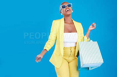 Buy stock photo Fashion, deal and black woman in studio with shopping, bag and glasses, excited and smile on blue background. Retail, store and African female customer happy with boutique, discount and mall sale