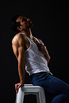 Sexy, muscle and man on chair on black background with fitness inspiration, beauty aesthetic and sensual fashion. Erotic art, sexual body and male model sitting in studio, thinking in dark lighting.