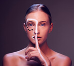 Woman, face and paint in finger, lips or studio for art, secret or cosmetic for fantasy by dark background. Girl, model and facial painting with hush sign, mouth or creativity with makeup in portrait