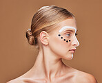 Art, cosmetic and young woman in studio with creative, beauty and abstract face aesthetic. Makeup, artistic and headshot of gen z female model from Australia with facial paint by brown background.