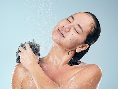 Buy stock photo Woman, shower and water drops with loofah in hygiene, grooming or washing against a blue studio background. Female person in relax for body wash, cleaning or skincare routine under rain in bathroom