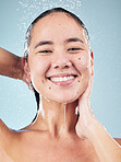 Skincare, water splash and face of woman cleaning in studio isolated on a blue background. Shower, hygiene and portrait of happy Asian model washing, cosmetic and bath for wellness, health and beauty