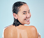 Skincare, shower back and face of woman cleaning in studio isolated on a blue background. Water splash, hygiene and portrait of happy Asian model washing in bath for wellness, health and body beauty