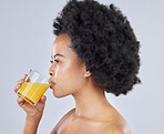 Woman, glass and orange juice in studio for beauty of vitamin c benefits on gray background. Face, african model and drink citrus fruit smoothie for healthy skin, weight loss diet and detox nutrition