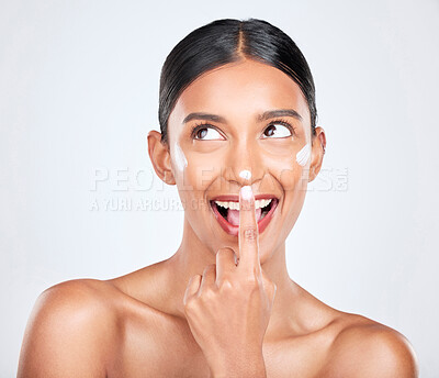 Buy stock photo Cream, woman and facial cosmetics in studio for aesthetic skincare, dermatology or smile on white background. Happy indian model, face lotion and thinking of beauty, sunscreen and healthy moisturizer