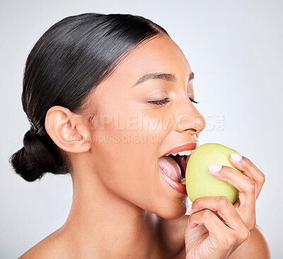 Buy stock photo Face, beauty and woman biting an apple for health, wellness or nutrition in studio on white background. Food, skincare and diet with a young model eating organic green fruit for benefits or digestion