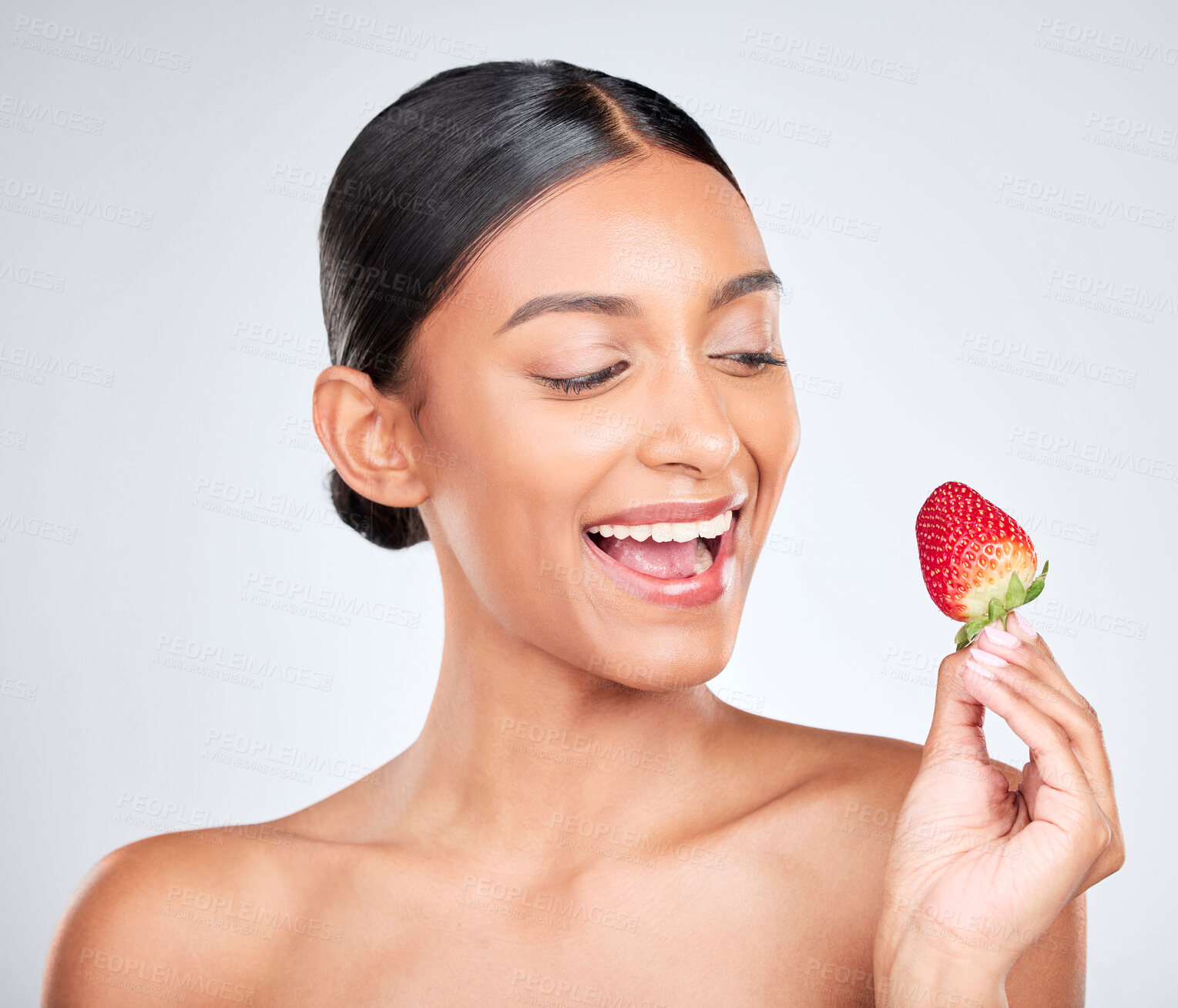 Buy stock photo Wellness, happy and woman with a strawberry in studio for healthy diet snack for nutrition. Health, beauty and young Indian female model with fruit for natural skin detox routine by white background.