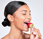 Diet, happy and woman eating strawberry in a studio for healthy diet snack for nutrition. Wellness, beauty and young Indian female model with fruit for natural skin detox routine by white background.