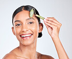 Portrait, beauty and facial massage roller with a woman in studio on a white background holding a stone. Face, smile and skincare with a happy young model looking confident at luxury wellness
