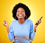Woman, phone and fist for success in studio, celebration and winning lottery prize, promotion or bonus on yellow background. Happy african model, mobile app and celebrate online gambling achievement