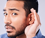 Whisper, portrait and hand on ear of man in studio with speak up, listen or announcement on grey background. Gossip, face and Asian guy model with emoji for what, pardon or curious, listening or news
