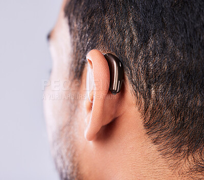 Buy stock photo Ear, deaf and hearing aid closeup in studio on a gray background for sound, audio or communication. Technology, listening and a man with a disability closeup for implant or medical innovation 