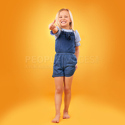 Buy stock photo Happy, portrait of child and thumbs up in studio for support, like emoji or yes approval. Excited girl kid on orange background or space for hand gesture, barefoot or sign for agreement or thank you