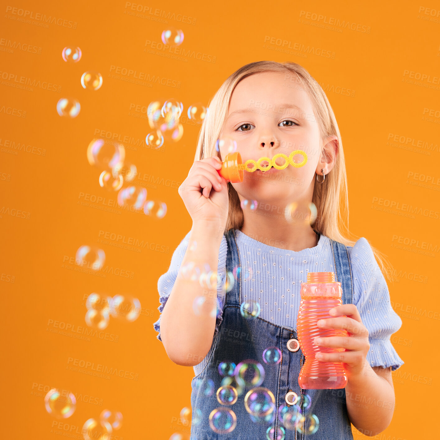 Buy stock photo Portrait, child and blowing bubbles in studio for fun, freedom and childhood development on orange background. Young girl, kid and learning to play with soap bubble wand, toys and activity games