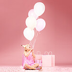 Balloons, birthday and girl on pink background for celebration, party and special day in studio. Happy, wonder and excited young child sitting with presents, gift box and decoration for festive event