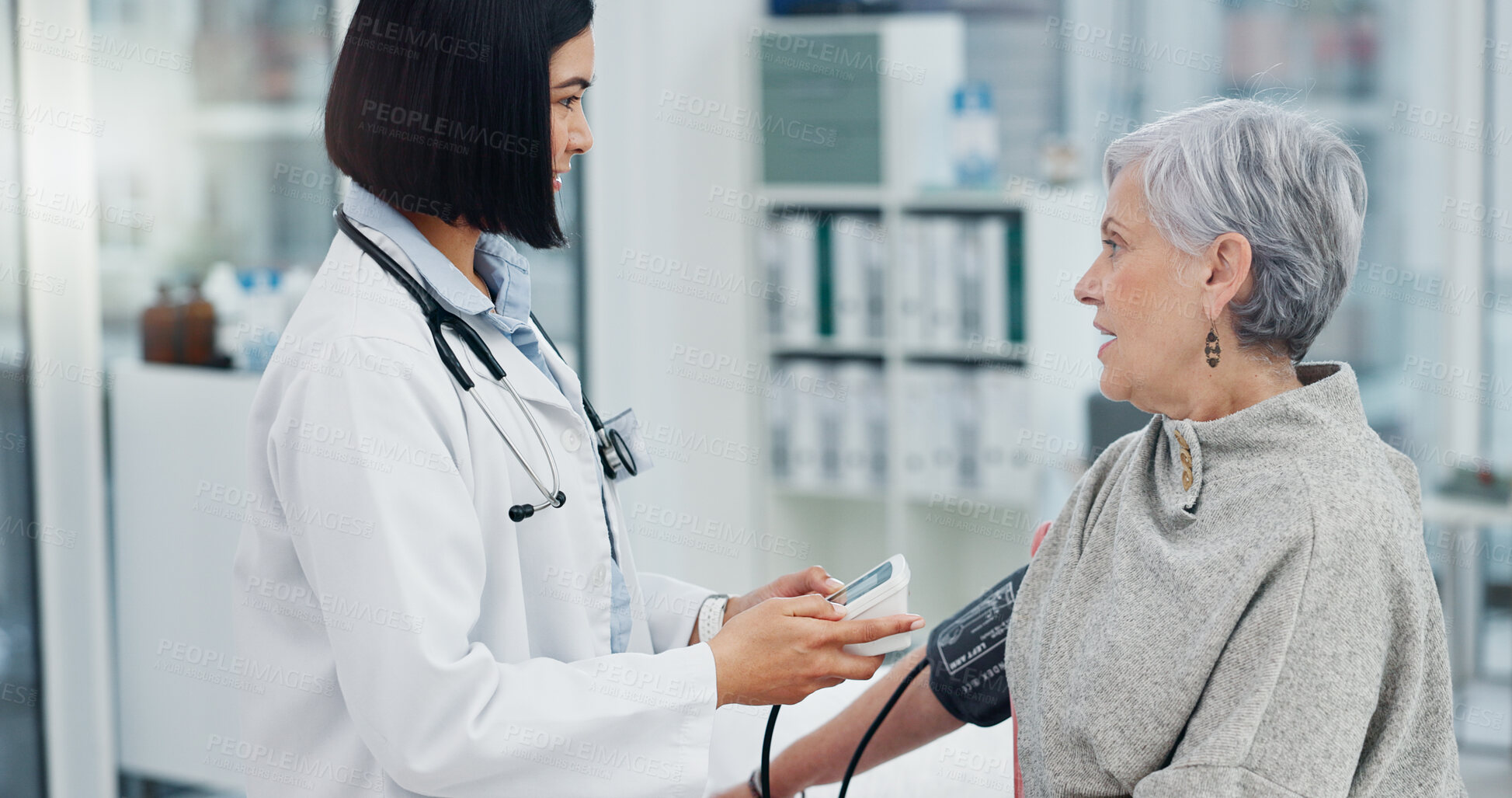 Buy stock photo Senior woman, blood pressure monitor and doctor in consultation for healthcare service in hospital. Smile, hypertension test and elderly patient with medical worker to check cardiology or heart beat