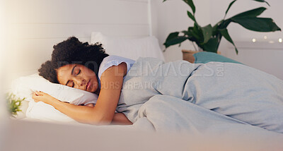 Young black woman sleeping in bed in her bedroom while resting and having a dream at home. Relax, peaceful and calm African girl taking a nap with a comfortable pillow and blanket at her house.