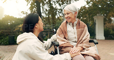 Wheelchair, park and a senior woman with a disability talking to her nurse during a walk together outdoor. Healthcare, medical and a female care chatting to an elderly patient or resident in a garden