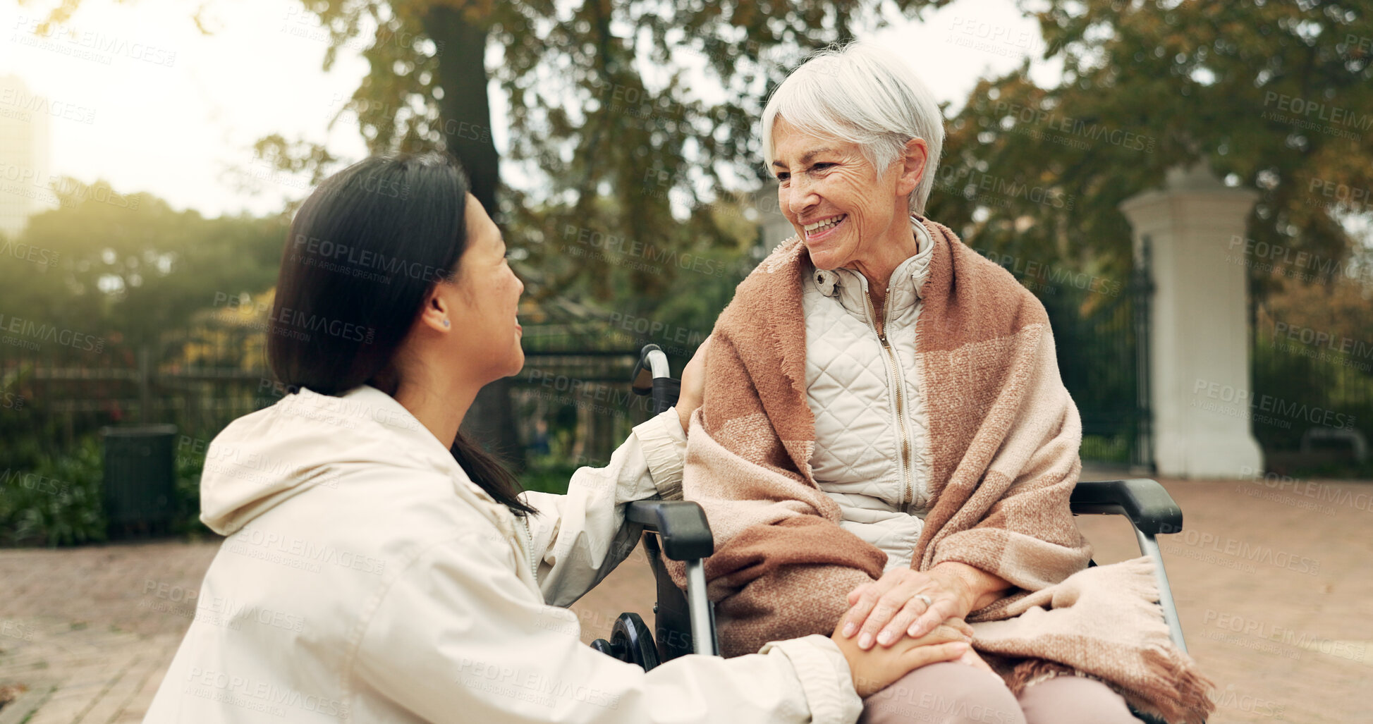 Buy stock photo Wheelchair, park and a senior woman with a disability talking to her nurse during a walk together outdoor. Healthcare, medical and a female care chatting to an elderly patient or resident in a garden