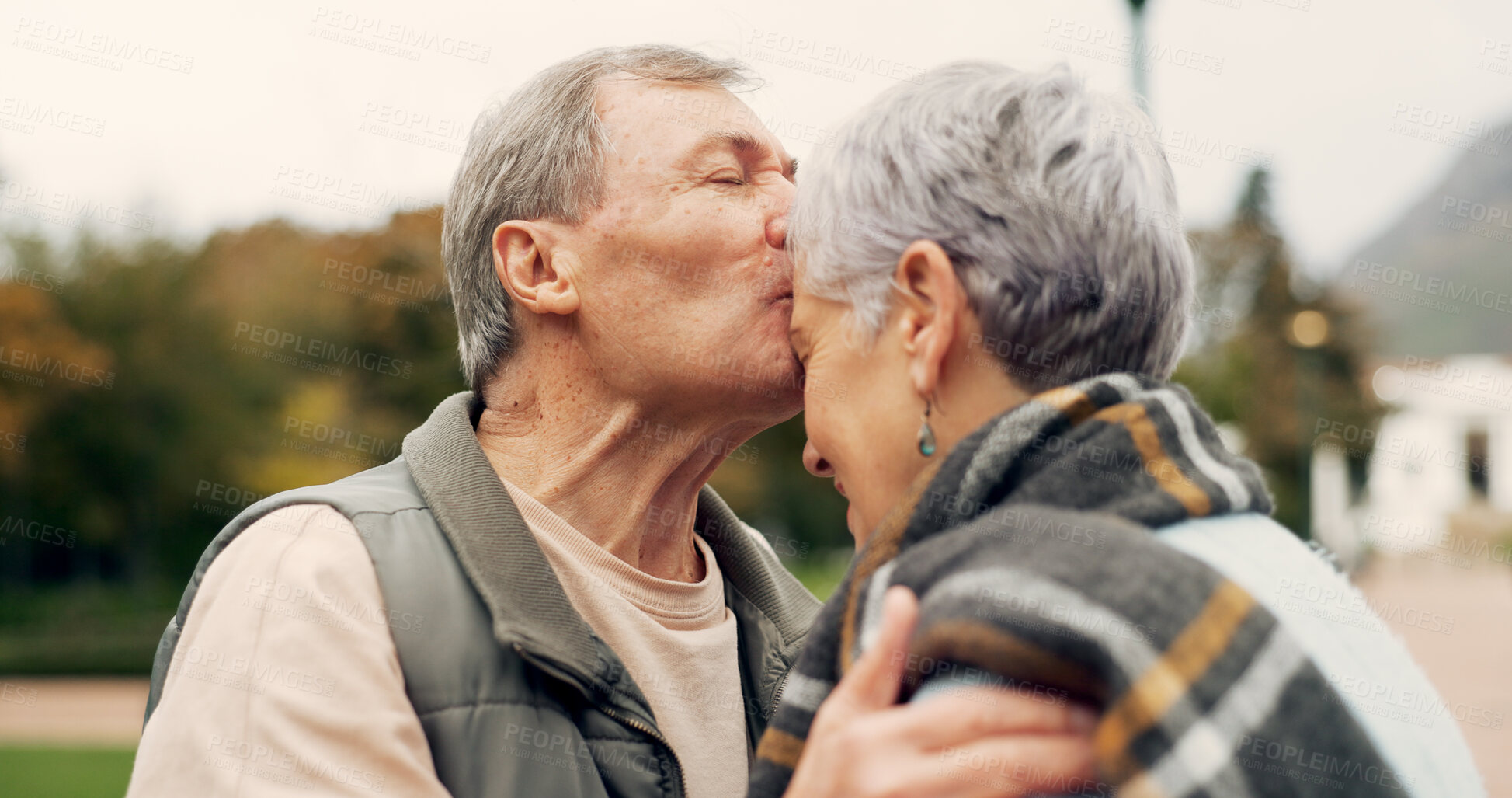 Buy stock photo Kiss, forehead and senior couple in a park with love, happy and conversation with romantic bonding. Kissing, old people and elderly man embrace woman with care, romance or soulmate connection outdoor